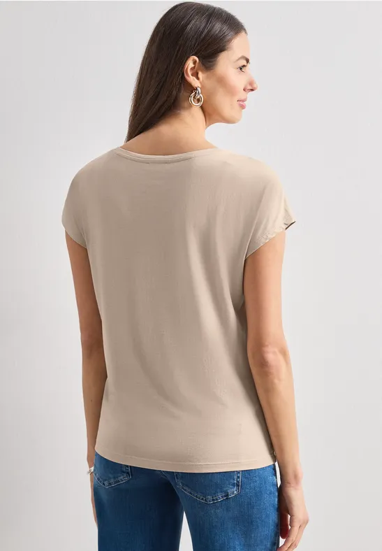 Frau von hinten in beigem Kurzarmshirt und Jeans.