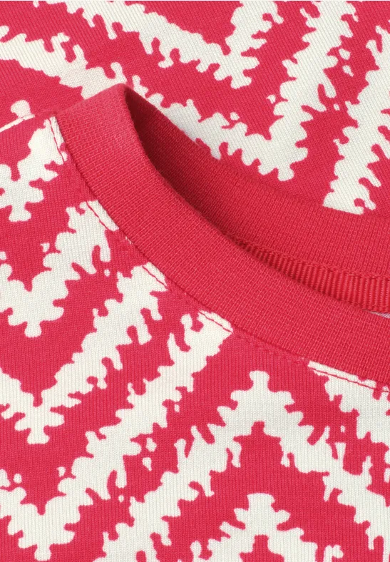 Nahaufnahme eines roten Strickshirts mit weißem Zickzackmuster.