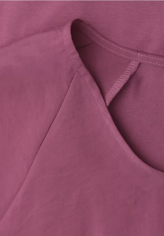 Close-up van een mouwloos topje in roze-paars, zachte stof, ronde hals en subtiele stiksels.