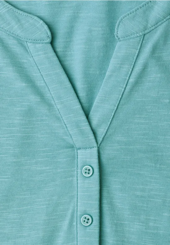 Gros plan sur un T-shirt turquoise à col en V avec trois boutons.
