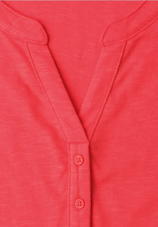Rotes Shirt mit V-Ausschnitt und zwei Knöpfen an der Leiste.
