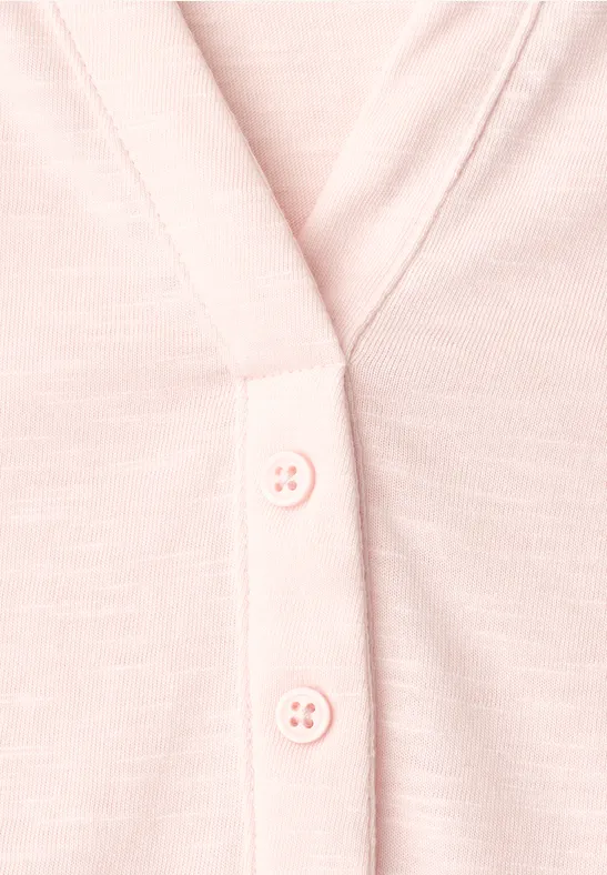 Close-up van een lichtroze vest met knoopsluiting