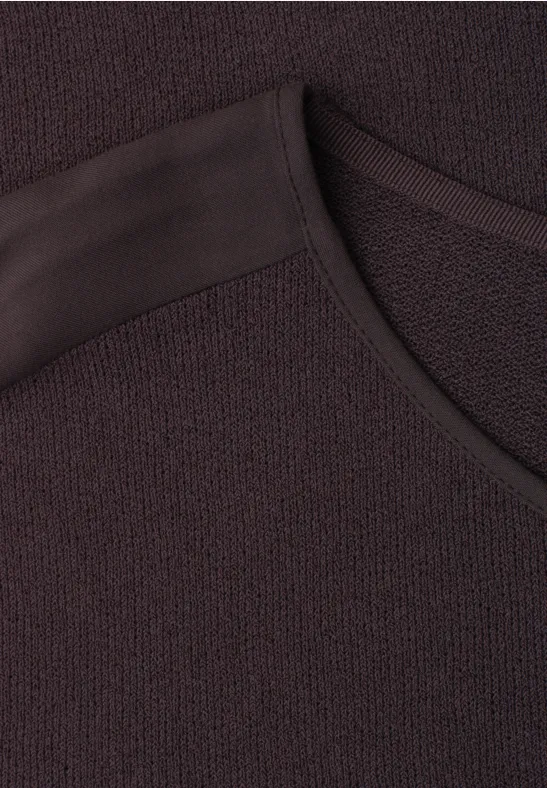 Nahaufnahme eines dunkelbraunen Strickshirts mit Rundhalsausschnitt und feiner Struktur.