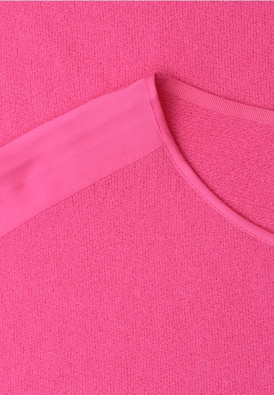 Close-up van een felroze T-shirt met ronde hals.