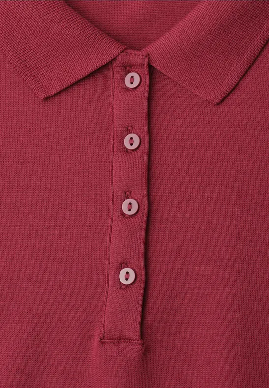 Close-up van een bordeauxrood poloshirt met omgeslagen kraag en vier knopen