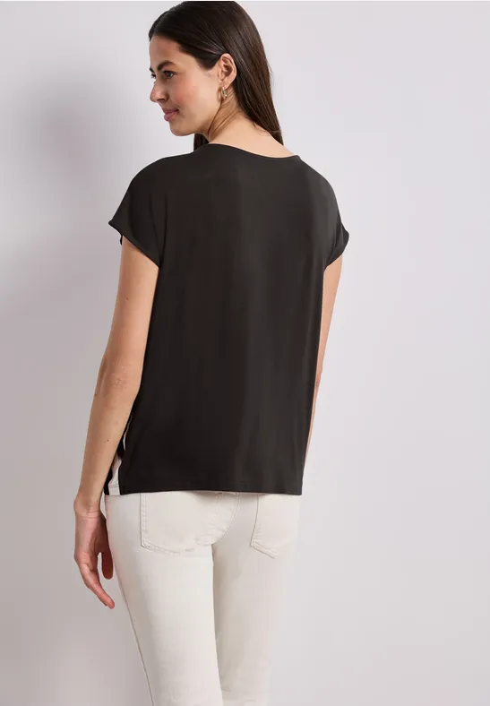 Vrouw van achteren met een zwart shirt en witte broek.