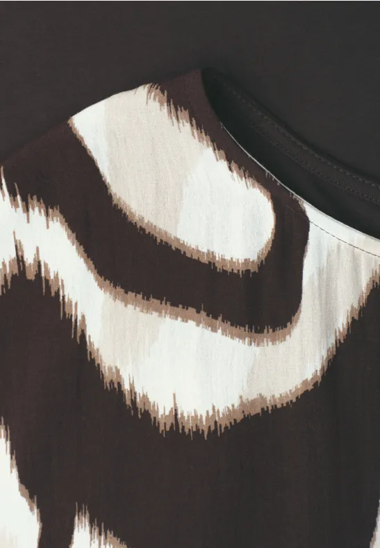 Close-up van stof met onregelmatige bruine en roomkleurige strepen op een lichte achtergrond.