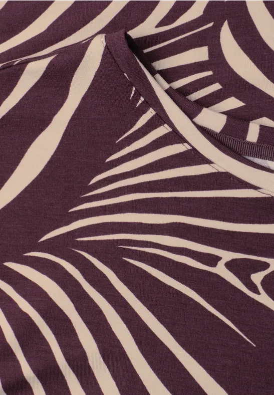 Nahaufnahme eines violetten Shirts mit cremefarbenem, abstraktem Zebramuster.