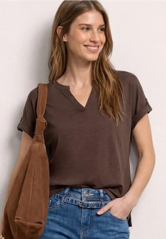 Femme portant un t-shirt brun à col V, un jean et un sac à bandoulière marron