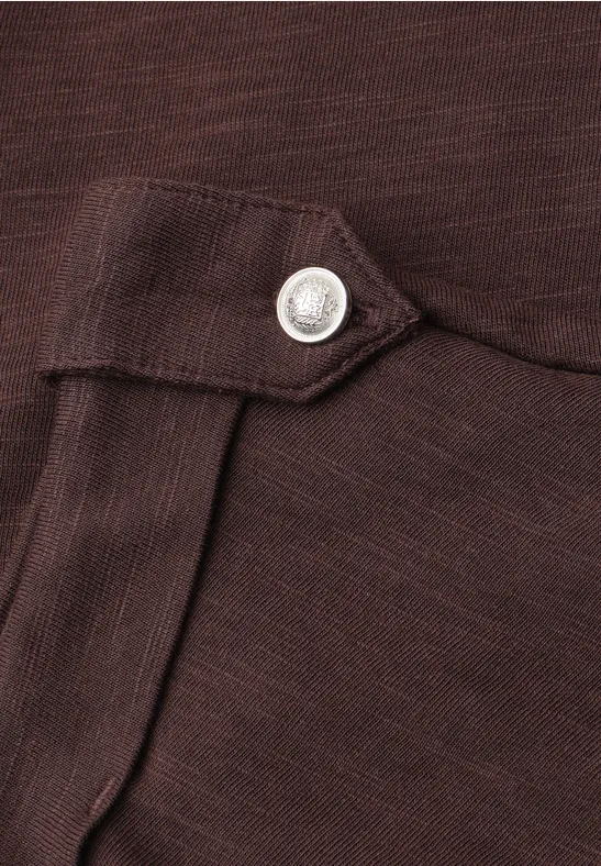 Gros plan d'un tissu marron avec un rabat et un bouton-pression argenté.