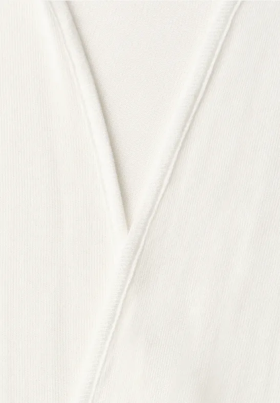 Close-up van een crèmewitte stof met een V-vormige naad.