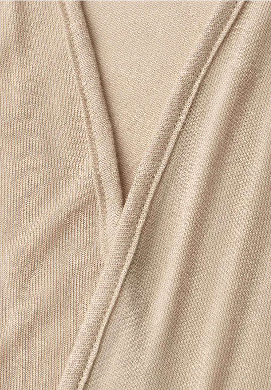 Detailopname van een beige gebreid stof met V-naad.