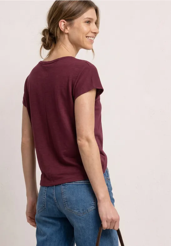 Vrouw van achteren in bordeauxrood t-shirt en blauwe jeans