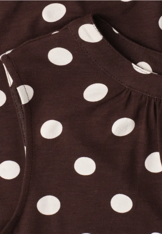 Braunes Kleidungsstück mit weißen Polka Dots und aufgesetzter Tasche.
