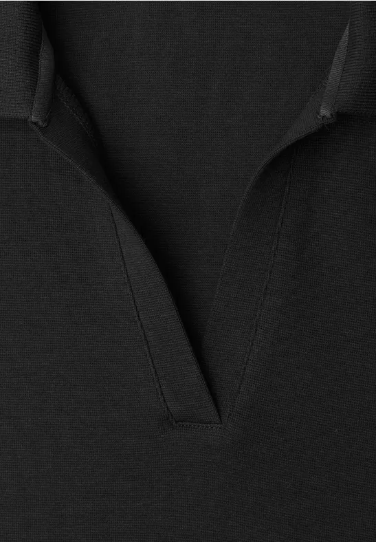 Close-up van een zwart kledingstuk met V-hals en fijne zichtbare naden.