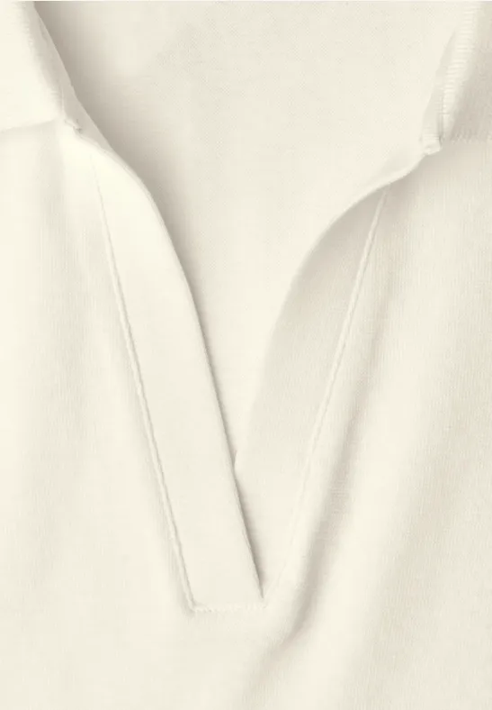 Close-up van lichtbeige kledingstuk met V-hals en subtiele stiknaden.