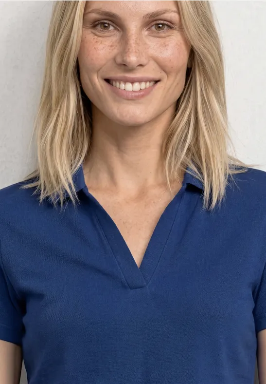 Vrouw met blond haar in een blauw poloshirt, gezicht wazig.