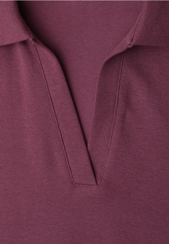 Close-up van een bordeauxrood poloshirt met een open V-hals.