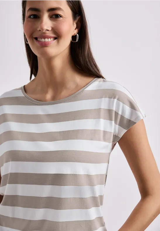 Eine lächelnde Frau in einem beige-weiß gestreiften T-Shirt vor hellem Hintergrund.