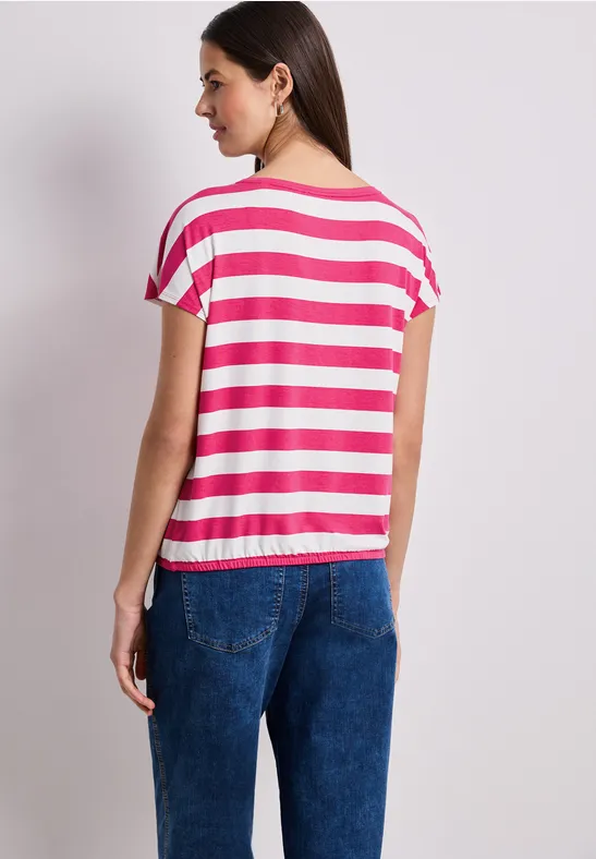 Frau von hinten in pink-weiß gestreiftem T-Shirt und blauen Jeans.