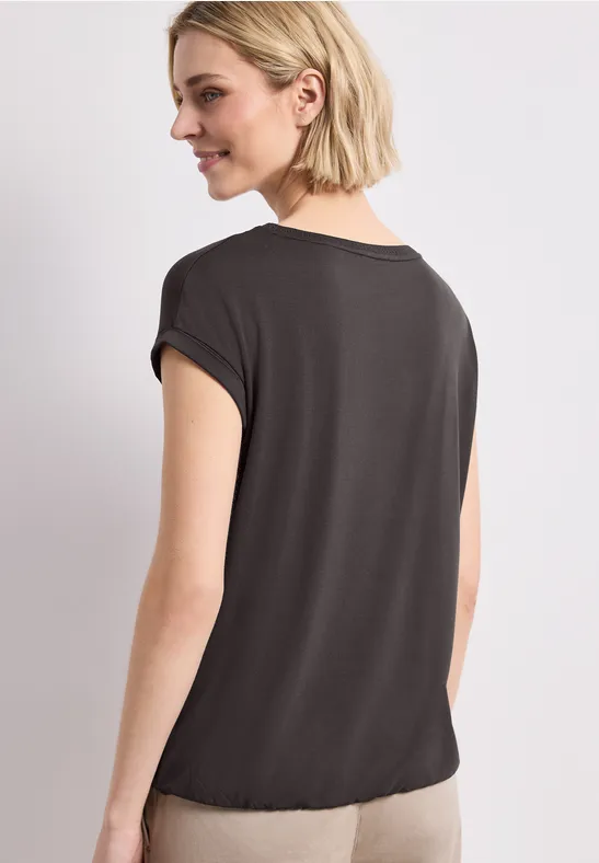 Achteraanzicht van een jonge vrouw met halflang blond haar die een zwart t-shirt draagt.