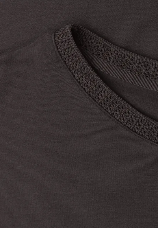 Close-up van een zwart T-shirt met ronde hals en fijne siernaad.