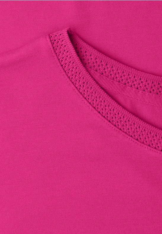 Nahaufnahme eines pinkfarbenen T-Shirt-Ausschnitts mit feinem Stoff und Ziernähten