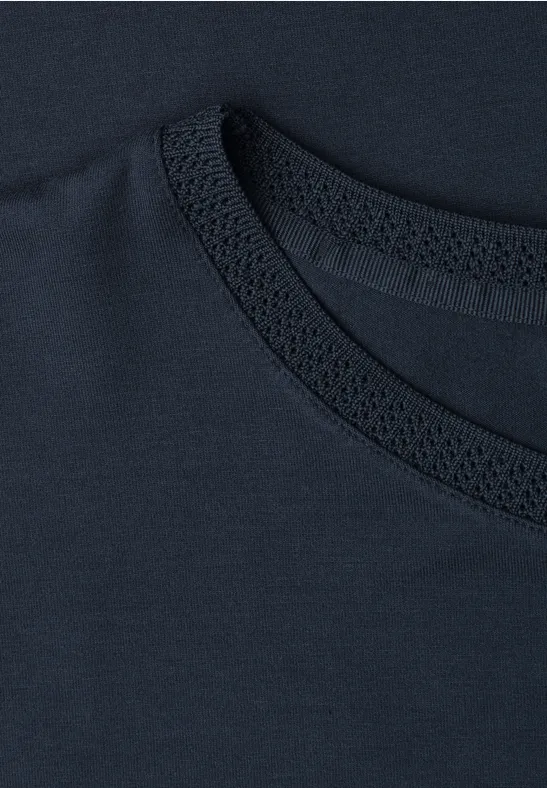 Close-up van de kraag van een donkerblauw T-shirt met stikseldetail.