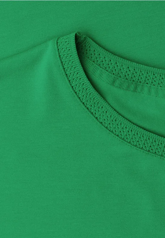 Nahaufnahme eines grünen T-Shirts mit Blick auf den Rundhalsausschnitt.