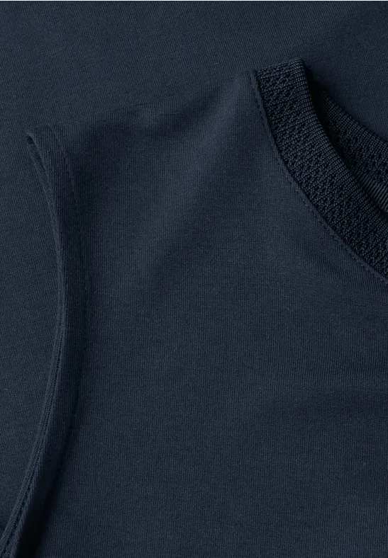 Close-up van een marineblauw mouwloos topje van zachte stof met zichtbare ronde halsnaad