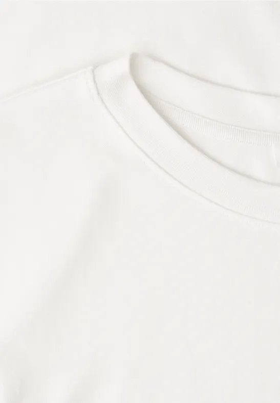 Twee gestapelde witte T-shirts op een lichte ondergrond