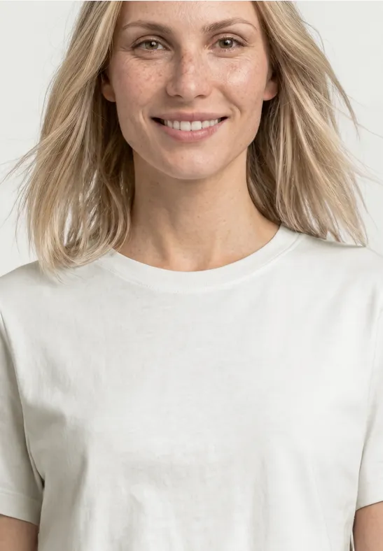 Vrouw met halflang blond haar in een eenvoudig wit T-shirt tegen een lichte achtergrond