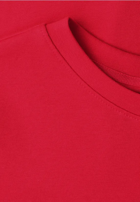 Close-up van een rood T-shirt met ronde hals.