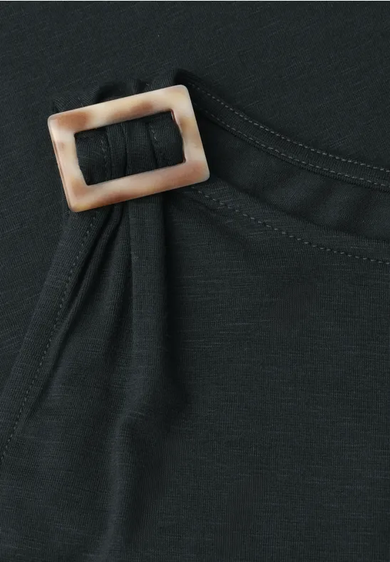 Zwart kledingstuk met rechthoekige beige-bruine gesp aan de zijkant