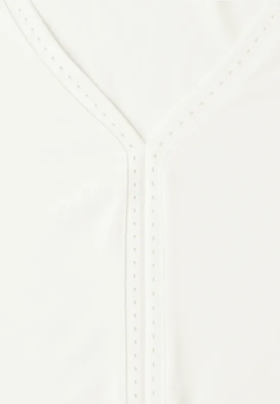 Weißes Kleidungsstück mit V-Ausschnitt und feiner Lochstickerei am Kragen.