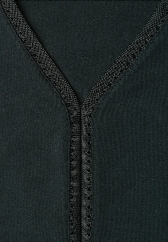 Close-up van een zwarte V-hals met siersteken en kleine perforaties