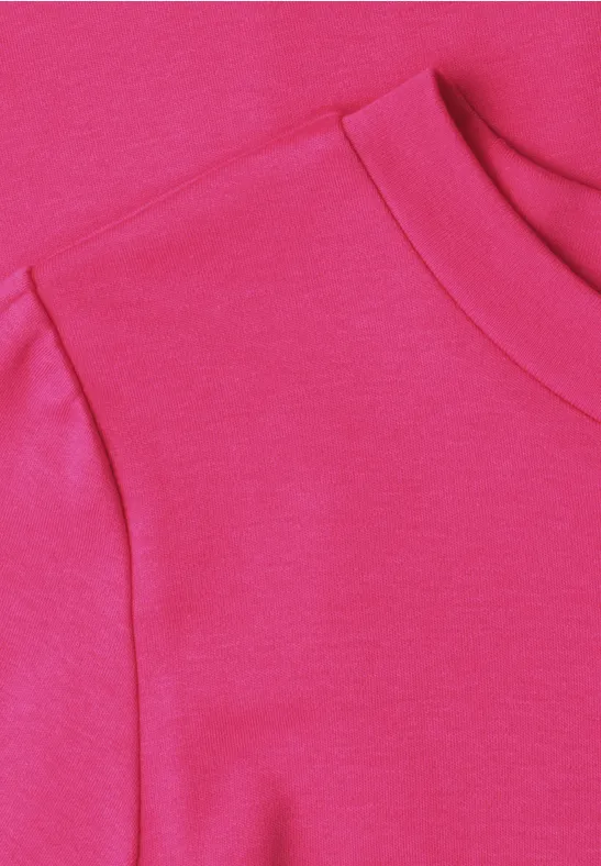Close-up van de halslijn van een roze t-shirt.