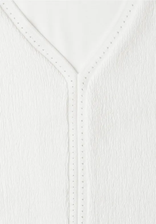 Witte, gestructureerde top met V-hals en fijne opengewerkte rand.