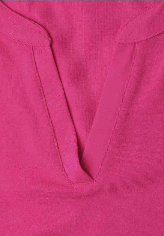 Nahaufnahme eines pinkfarbenen Oberteils mit V-förmigem Ausschnitt und sichtbarer Naht.