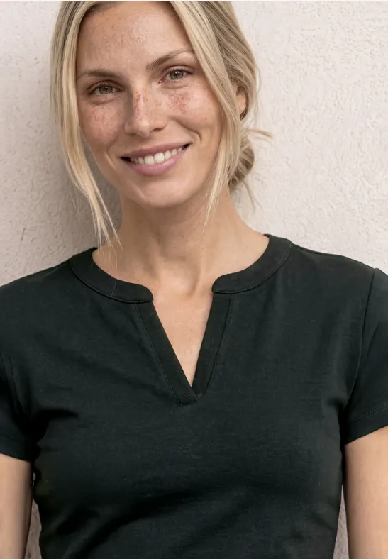 Vrouw in een eenvoudig zwart T-shirt, bovenlichaam tot de hals zichtbaar, gezicht vervaagd.