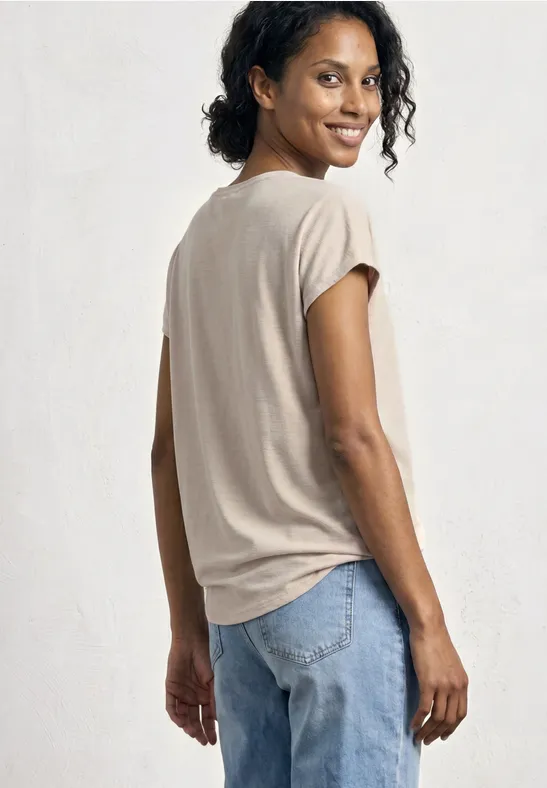 Achteraanzicht van een persoon in een beige t-shirt en jeans voor een lichte achtergrond.