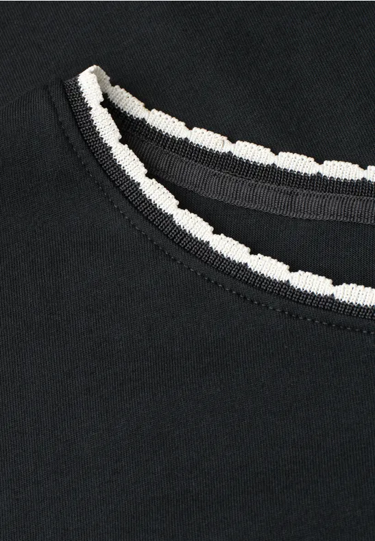 Schwarzes Oberteil mit rundem Ausschnitt und weißer, gezackter Einfassung.