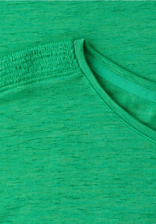 Gros plan d’un t-shirt vert chiné, col rond et tissu légèrement texturé.