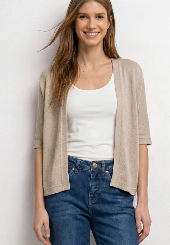 Frau trägt weißen Tanktop, beigen Kurzarm-Cardigan und blaue High-Waist-Jeans.