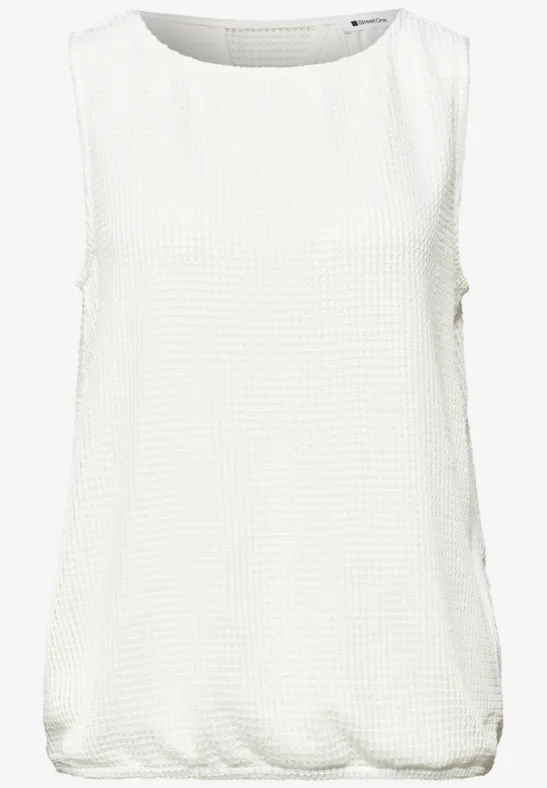Mouwloze witte top, losse pasvorm, ronde hals en subtiele textuur.