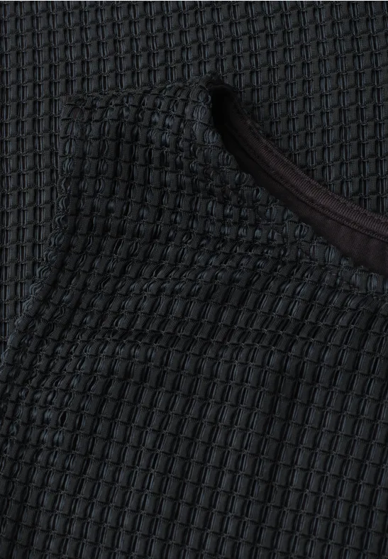 Close-up van donkergrijs gestructureerd gebreid textiel met ronde hals.