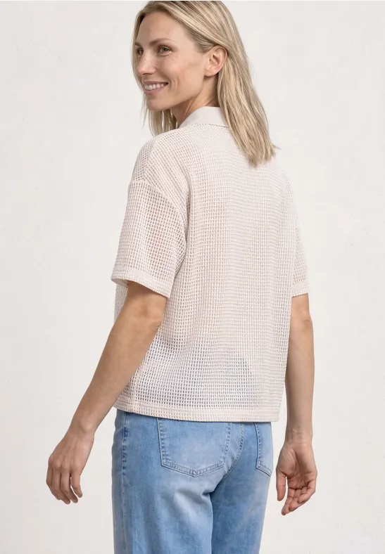 Vrouw van achteren in wit netshirt en blauwe spijkerbroek.