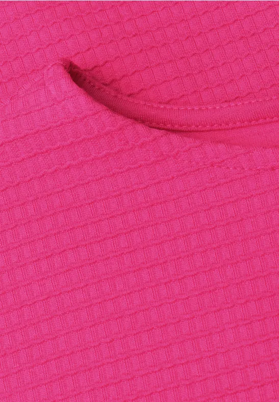 Close-up van een roze, gestructureerde stof met wafelmotief en een ronde opening