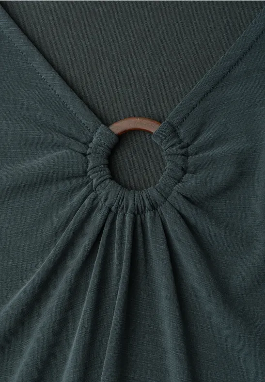 Donkergrijs kledingstuk met stof die rond een ring is gerimpeld.