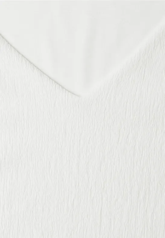 Nahaufnahme einer weißen, strukturierten Stoffoberfläche mit V-förmiger Falte.